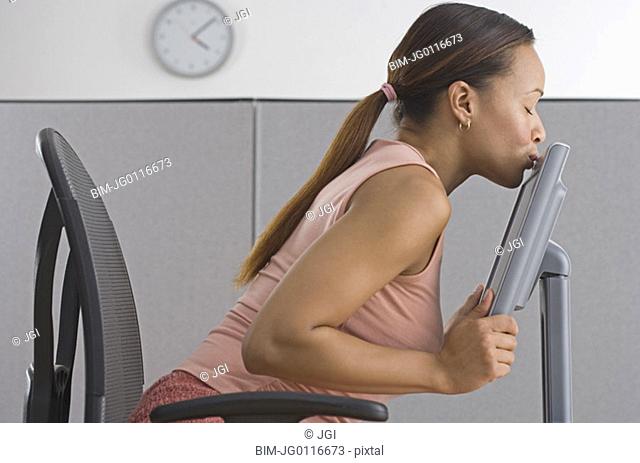 Woman in office kissing computer monitory
