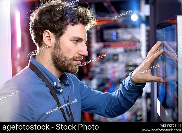 Male IT technician looking at computer screen in data center