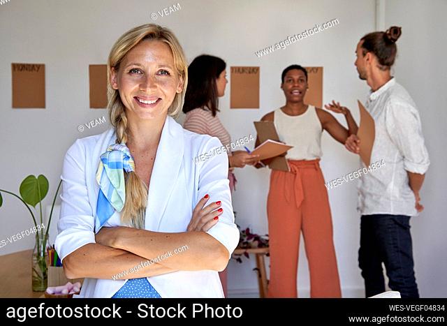 Blond businesswoman with arms crossed standing in office