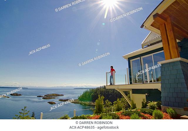 Young man overlooks the Copeland Islands and Desolation Sound Marine Park from a luxurious home in Sharpes Bay, near Lund on British Columbia's Sunshine Coast...