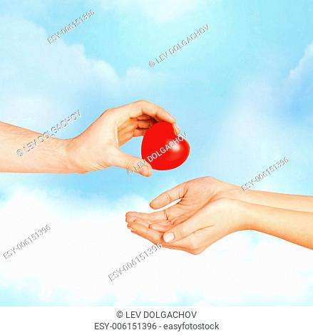 love, relationship, charity and medicine concept - man hand giving red heart to woman