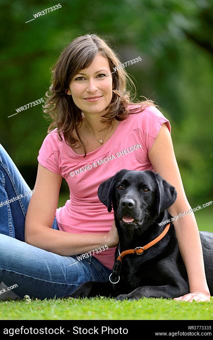 Woman with a black labrador on a meadow, Bavaria, Germany, Europe