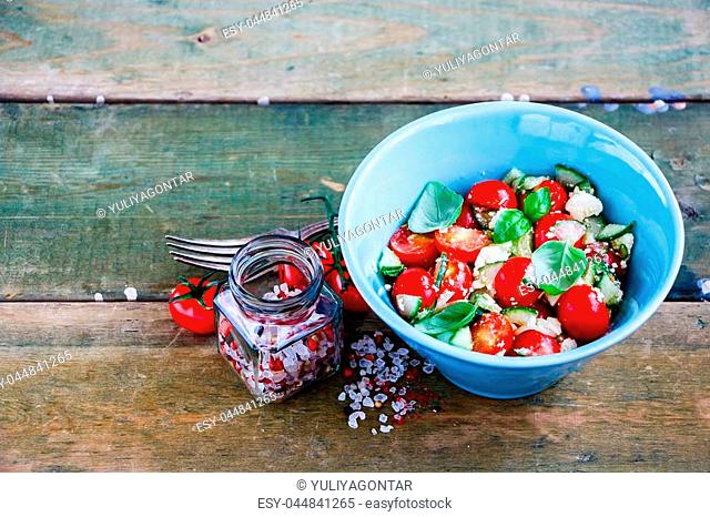 Organic summer vegetables and feta cheese salad in bowl on grunge wooden background, selective focus. Weight loss clean eating, vegan, vegetarian, healthy