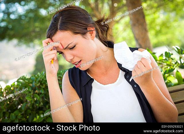 Frustrated and Upset Young Woman with Pencil and Crumpled Paper in Her Hand Sitting on Bench Outside