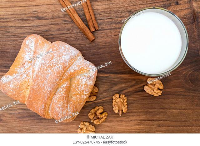 Image of tasty breakfast concept - sweet sugar coated walnut bun with glass of milk