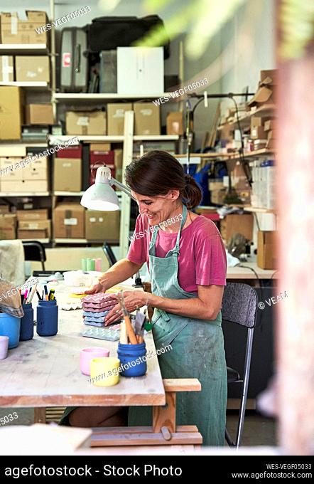 Smiling female store owner arranging concrete designs while working in workshop
