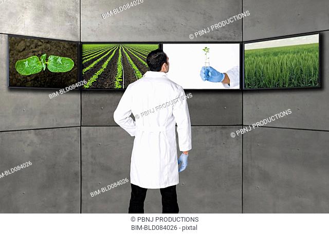 Hispanic scientist looking at images on television screens