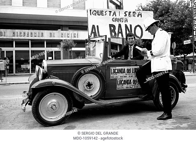 Al Bano with a traffic policeman. A traffic policeman pretending to fine the Italian singer and actor Al Bano (Albano Carrisi). Rimini, 1960s