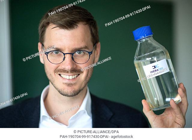 06 May 2019, Baden-Wuerttemberg, Eggenstein-Leopoldshafen: Tim Böltken, one of the managing directors of Ineratec GmbH, has a bottle containing synthetic fuel...