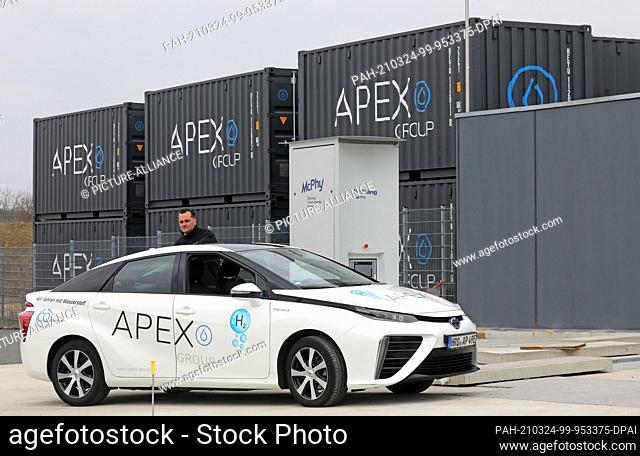 24 March 2021, Mecklenburg-Western Pomerania, Laage: Jörn Hennig, Technical Manager, demonstrates at APEX Energy Teterow GmbH the refuelling of an electric car...