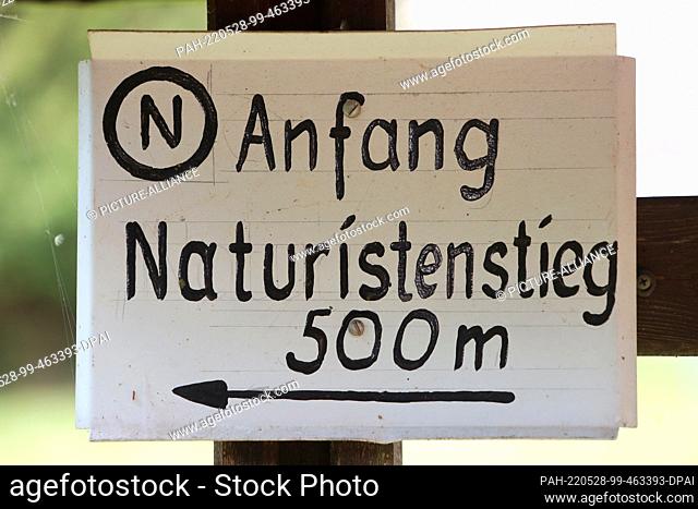 28 May 2022, Saxony-Anhalt, Wippra: A hiking sign with the inscription ""Naturistenstieg"" is attached to the dam in Wippra
