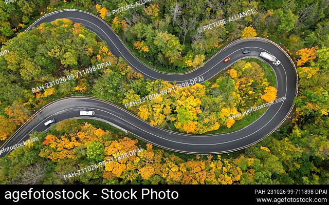 26 October 2023, Saxony-Anhalt, Blankenburg: The forests in the Harz Mountains near Blankenburg are colorful in autumn. A car drives in serpentines from...