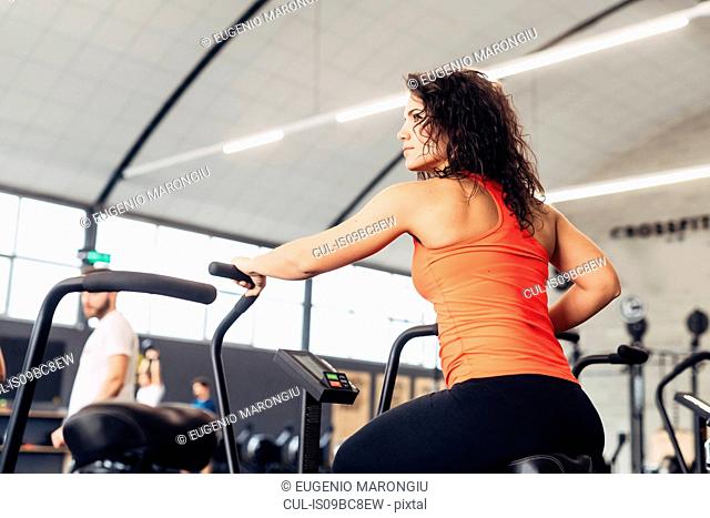 Rear view of woman on exercise bike in gym