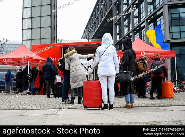 17 March 2022, Berlin: Refugees from Ukraine queue up outside Berlin's main train station to get SIM cards from a car belonging to the telecommunications...