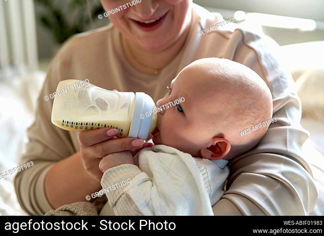 Mother feeding milk to baby girl at home