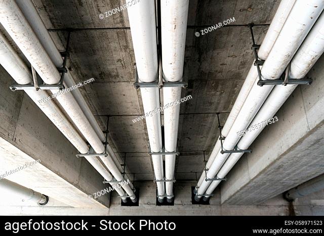 white industrial sewage and water pipes underneath a concrete bridge in Switzerland