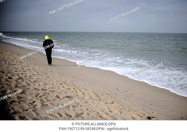 19 February 2019, Schleswig-Holstein, Sylt: A young man walks along the beach. Sylt is the largest North Frisian island in Germany