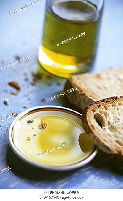 Olive oil on plate with slices of bread & olive oil bottle