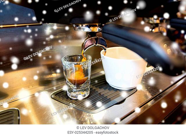 equipment, drinks and technology concept - close up of espresso machine making coffee over snow