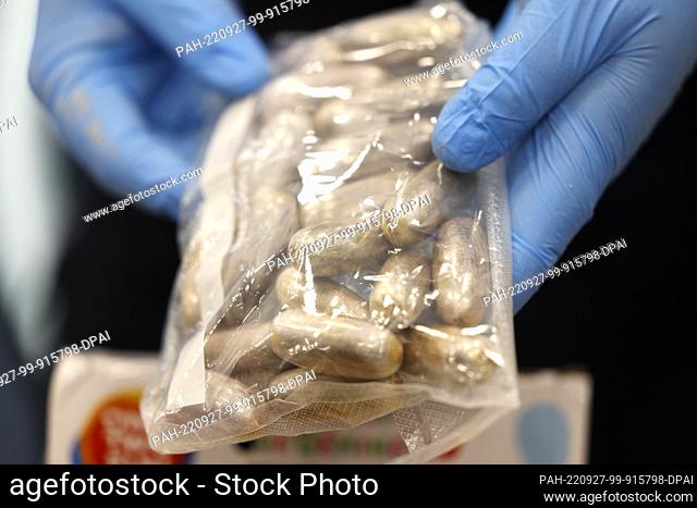 27 September 2022, North Rhine-Westphalia, Cologne: A customs officer holds so-called bodypacks filled with hashish into the camera