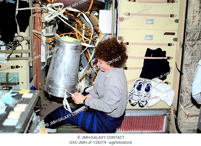 Susan J. Helms, Expedition Two flight engineer, works with a strap on a water container in the Zvezda Service Module. The image was taken with a digital still...
