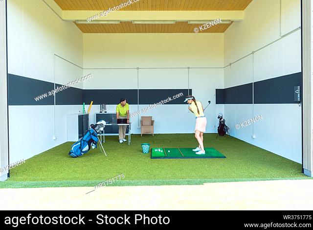 Full length view of a dedicated golf coach using modern equipment, while teaching a young woman the correct movement for striking the ball as a professional...