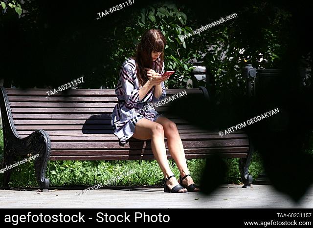 RUSSIA, MOSCOW - JULY 3, 2023: A woman sits on a bench on Spasopeskovskaya Square. Artyom Geodakyan/TASS
