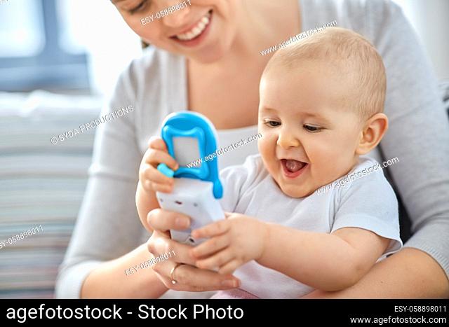 mother with baby playing with toy phone at home