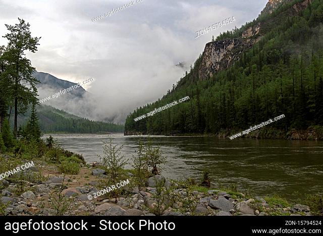 Low clouds in a mountain gorge. The beginning of the Orkho-Bom gorge, along this gorge the Sayan Oka river crosses the Sayansk ridge
