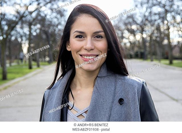 Portrait of smiling young woman with nose piercing in a park