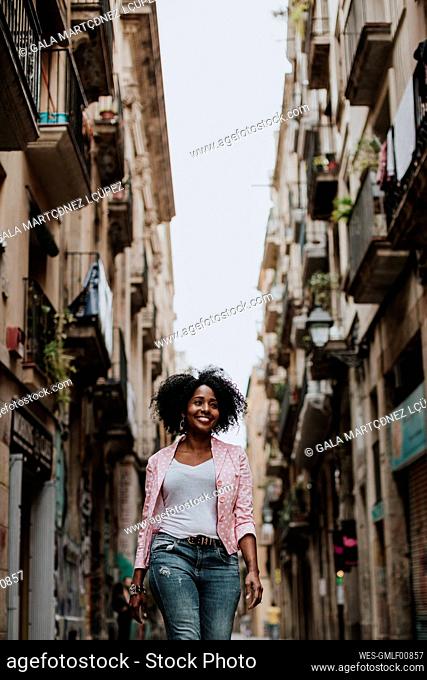 Smiling thoughtful woman walking in city