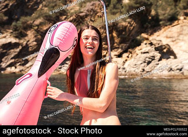 Happy teenage girl holding flamingo air mattress
