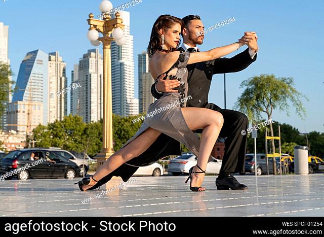 Male and female dancers practicing on footpath against sky during summer