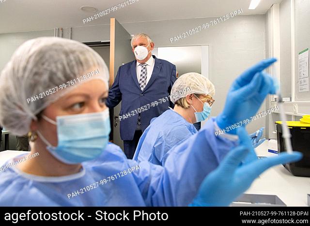 27 May 2021, North Rhine-Westphalia, Bielefeld: A pharmaceutical technical assistant (PTA) holds a syringe with vaccine in her hand in the pharmacy of the...