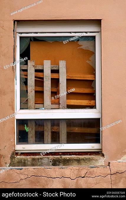 Sperrmüll wie Möbel und Holzabfälle stehen hinter einer zerbrochenen Fensterscheibe
