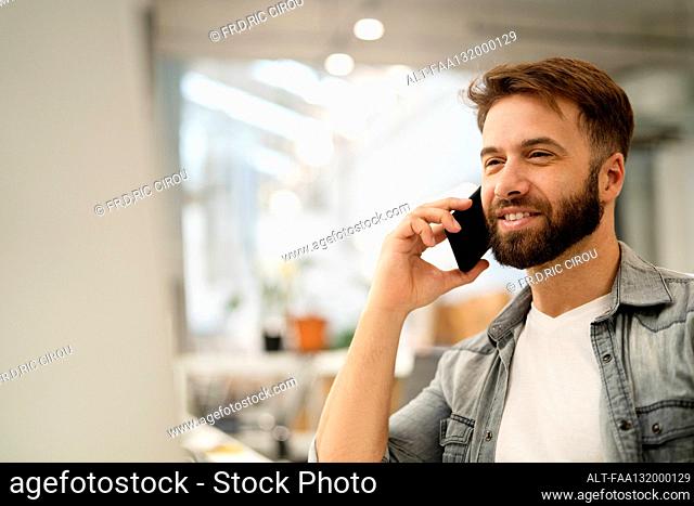 Male system engineer listening to voice mail while using computer