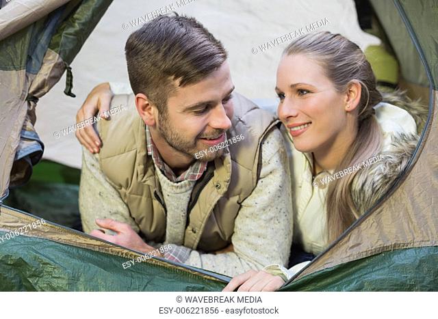 Smiling couple lying in tent after a hike