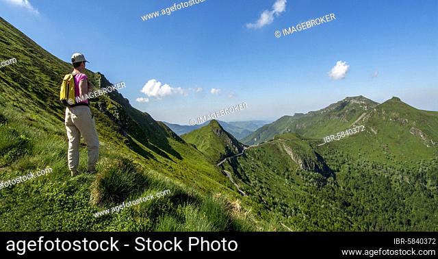 Hiker overlooking mountains, Auvergne Volcanoes Regional Natural Park, Cantal department, Auvergne-Rhone-Alpes, France, Europe