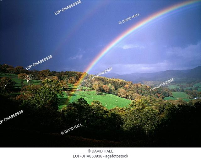 Wales, Denbighshire, Near Llangollen, Storm light with rainbow against dark skies over Welsh hills