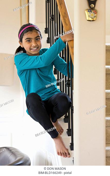 Indian girl climbing on staircase banister