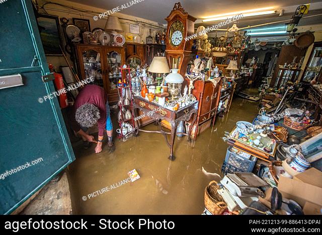 13 December 2022, Portugal, Lissabon: The owner of an antique store is in his flooded store. Heavy rains have caused damage to streets