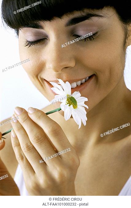 Young woman smelling flower, smiling, eyes closed