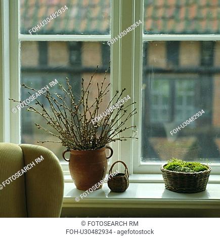 Close-up of spring branches in pottery vase on window sill