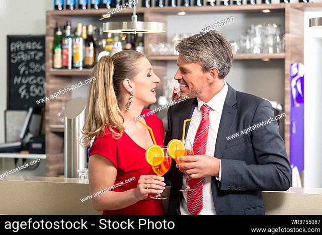 Mid adult couple looking each other while holding a cocktail