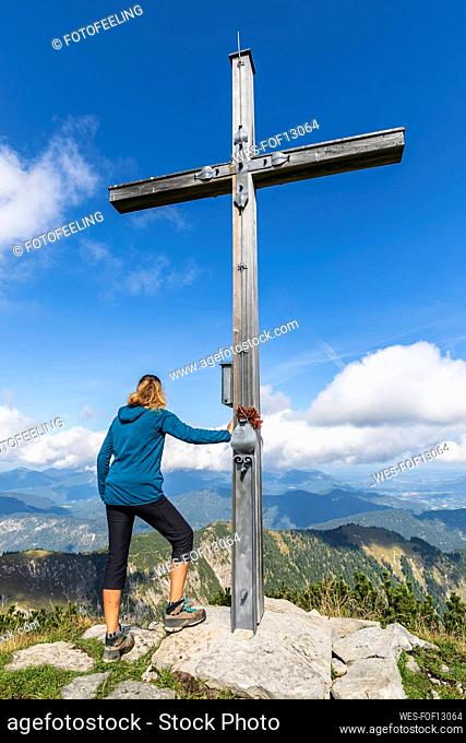 Female hiker standing by summit cross of Demeljoch mountain
