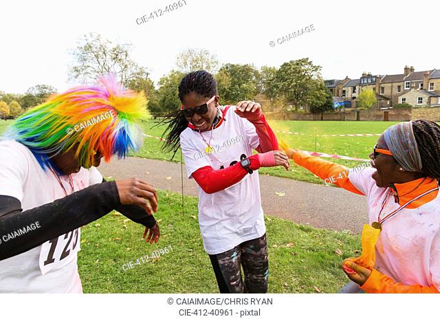 Playful runners celebrating, throwing holi powder at charity run in park
