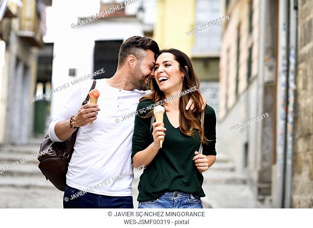 Happy tourist couple with ice cream cones in the city