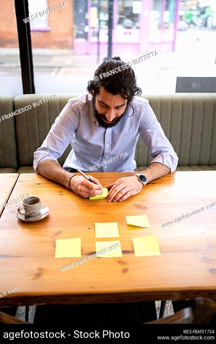 Bearded male entrepreneur writing on adhesive notes in office