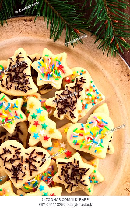 Homemade baked sugar cookies for Christmas with icing and colorful sprinkles on the top, served on enamel plate, photographed overhead