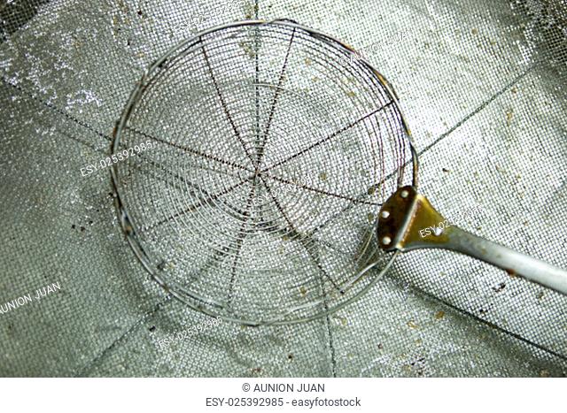 Skimmer driping oil over sieve. Used for cooking with fried food